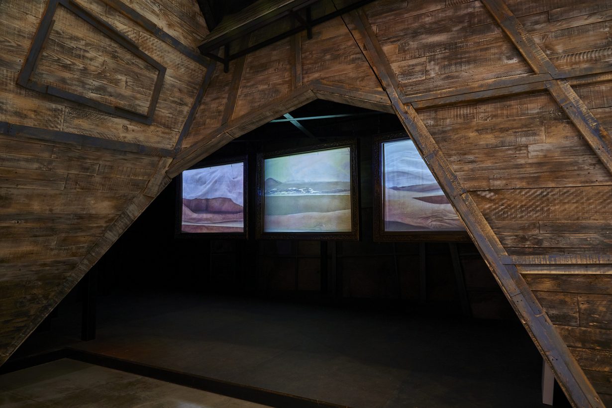 木製の壁に取り付けられた3つのスクリーンに映し出された風景