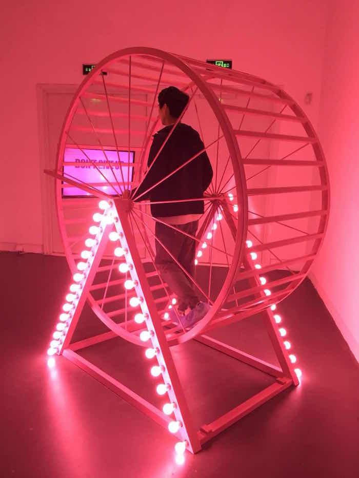 Wang Xin, Hamster Wheel, 2016, steel pipe, light bulb, LCD television, wire. Image: courtesy the artist and de Sartre Gallery, Hong Kong