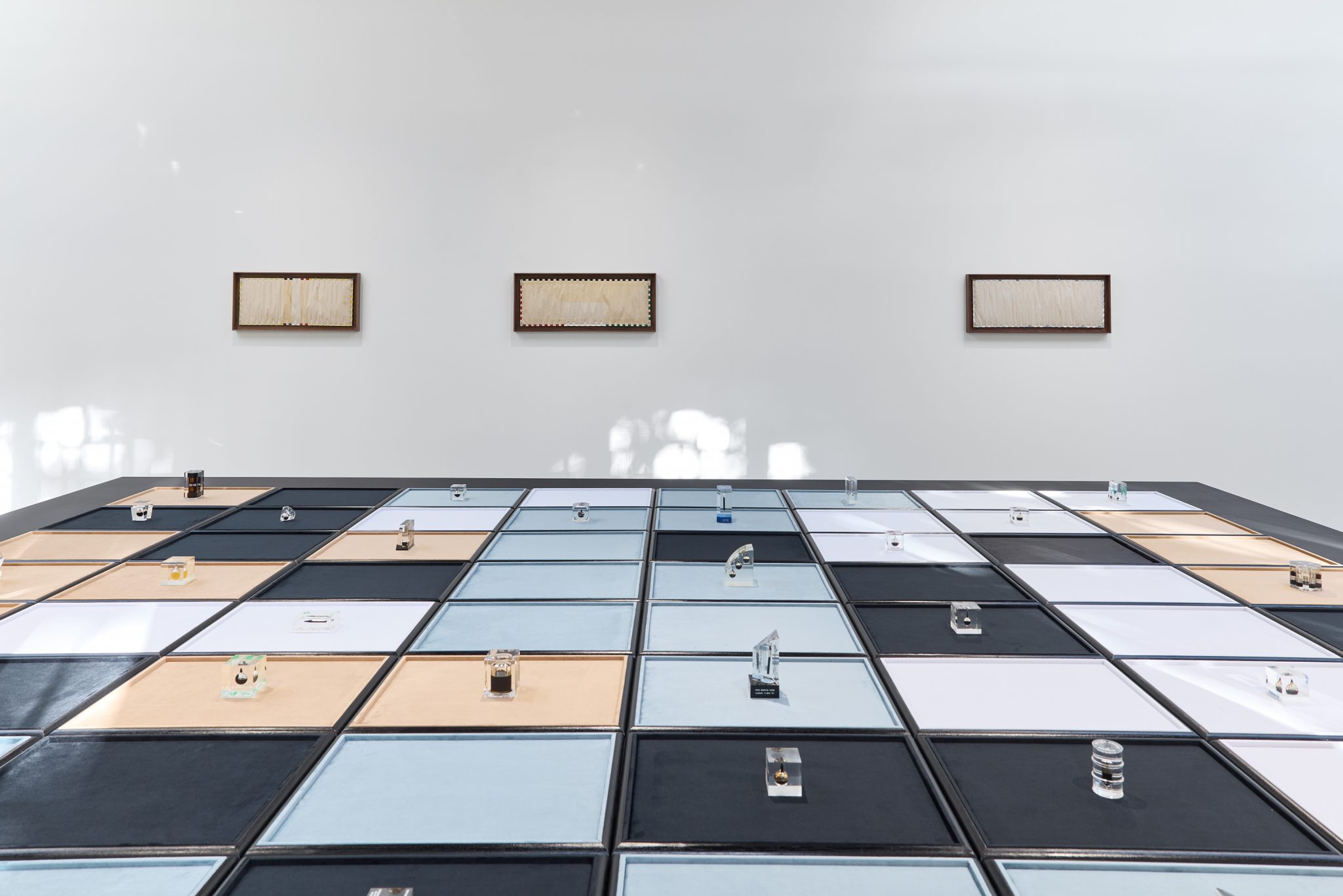 A gallery room with a large coloured grid and three rectangular wall works