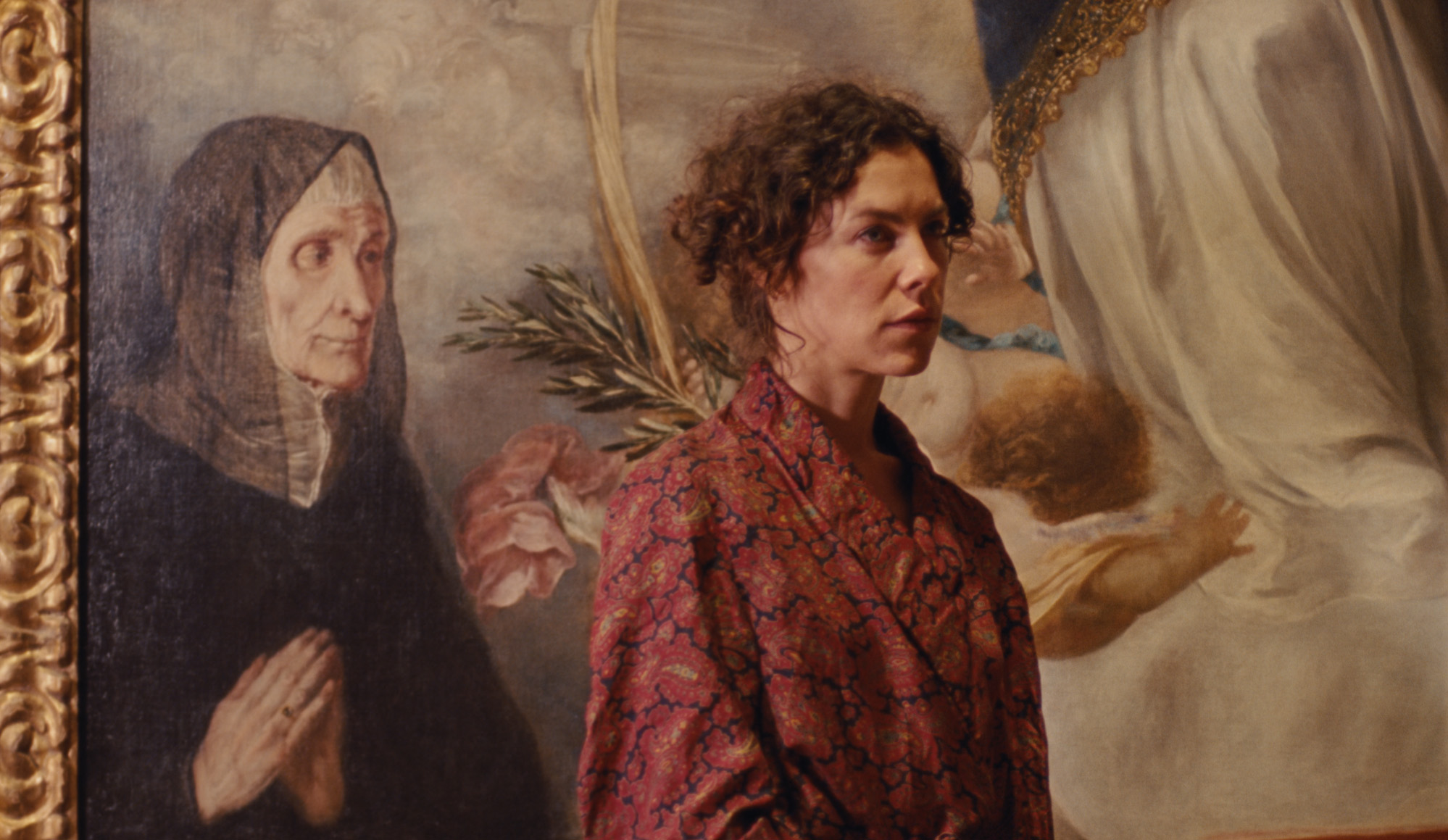 A film still showing a person standing in front of a painting