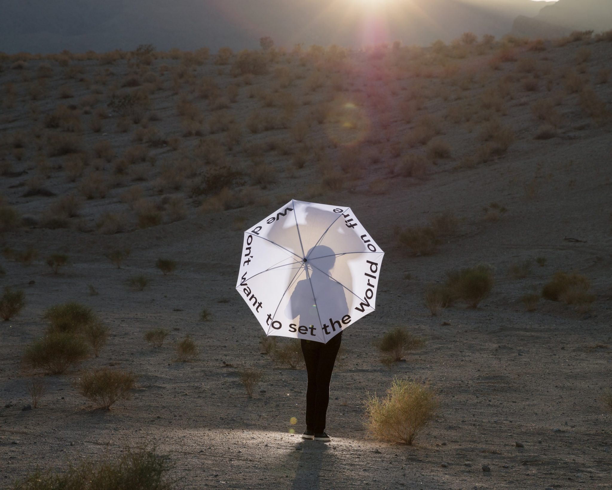 An image of a person standing with an umbrella in a desert
