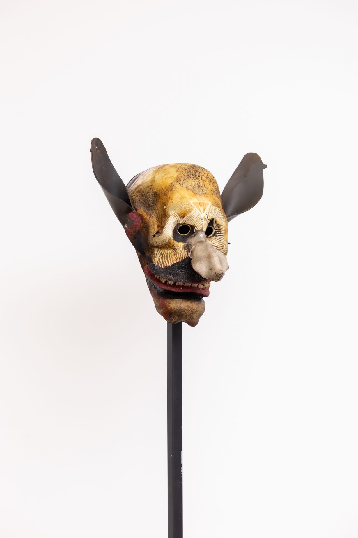 A skull mask on a wooden pole