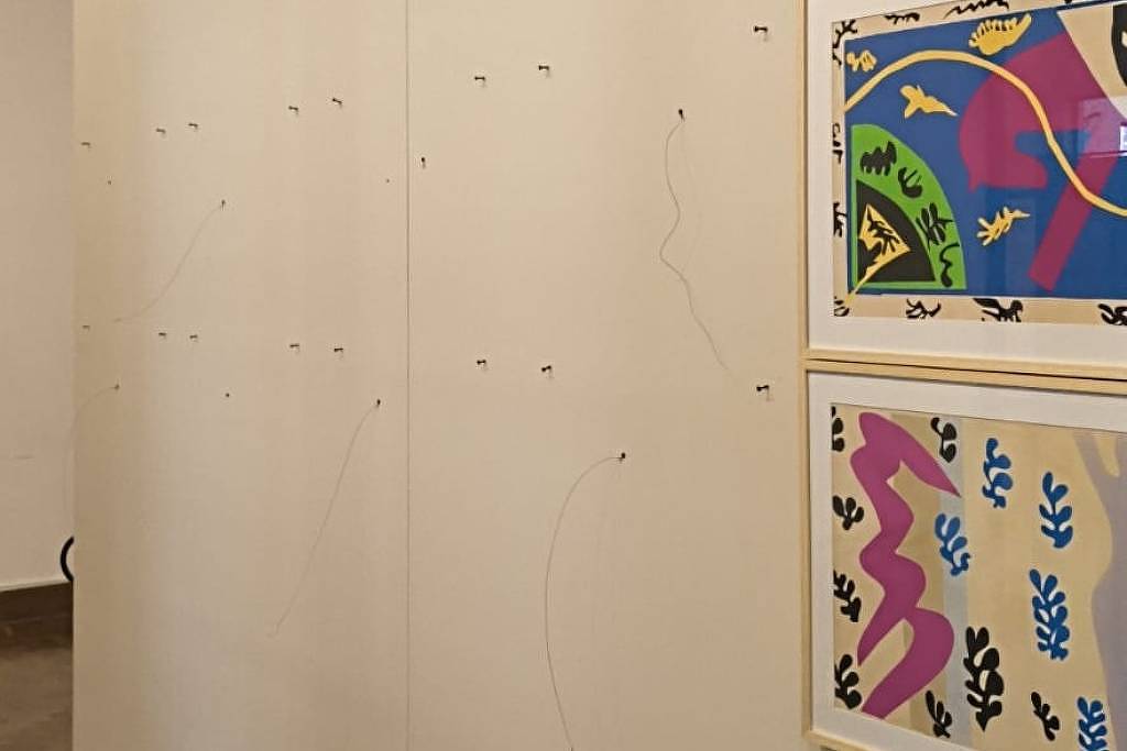 Photo show the space left behind on a gallery wall after the theft of two prints by Matisse. Security wires hand from the wall.