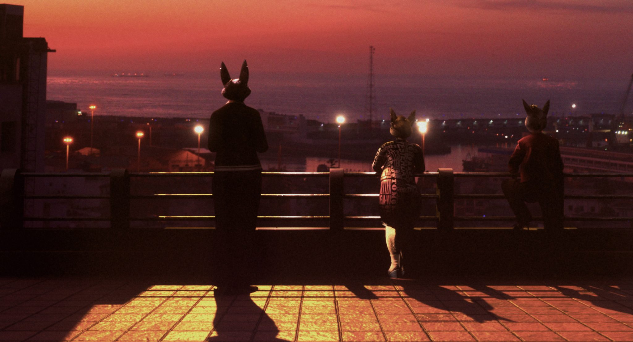 Three figures wearing bunny masks looking onto sunset