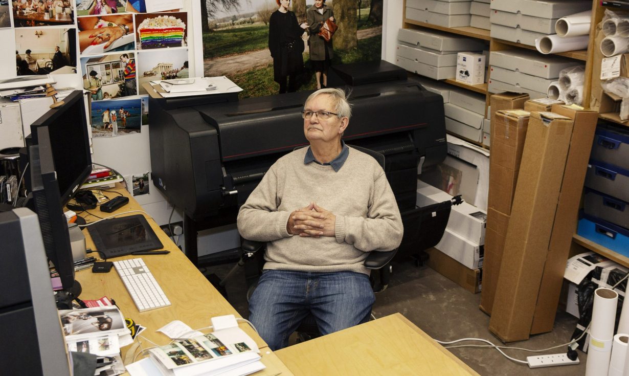Martin Parr sitting in his studio surrounded by photograph prints