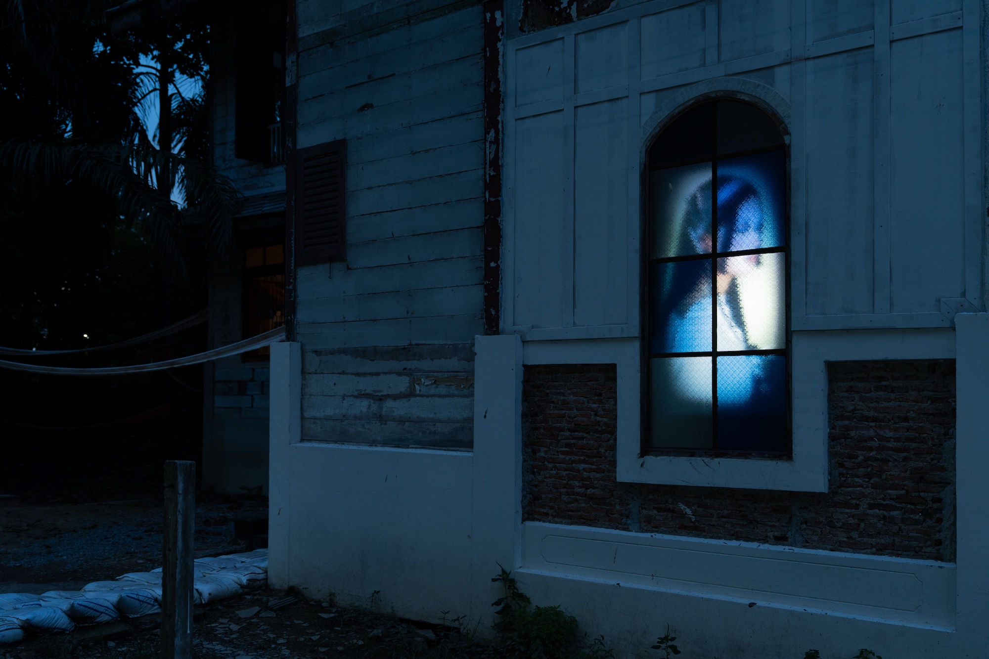 A lit up blue window on a house