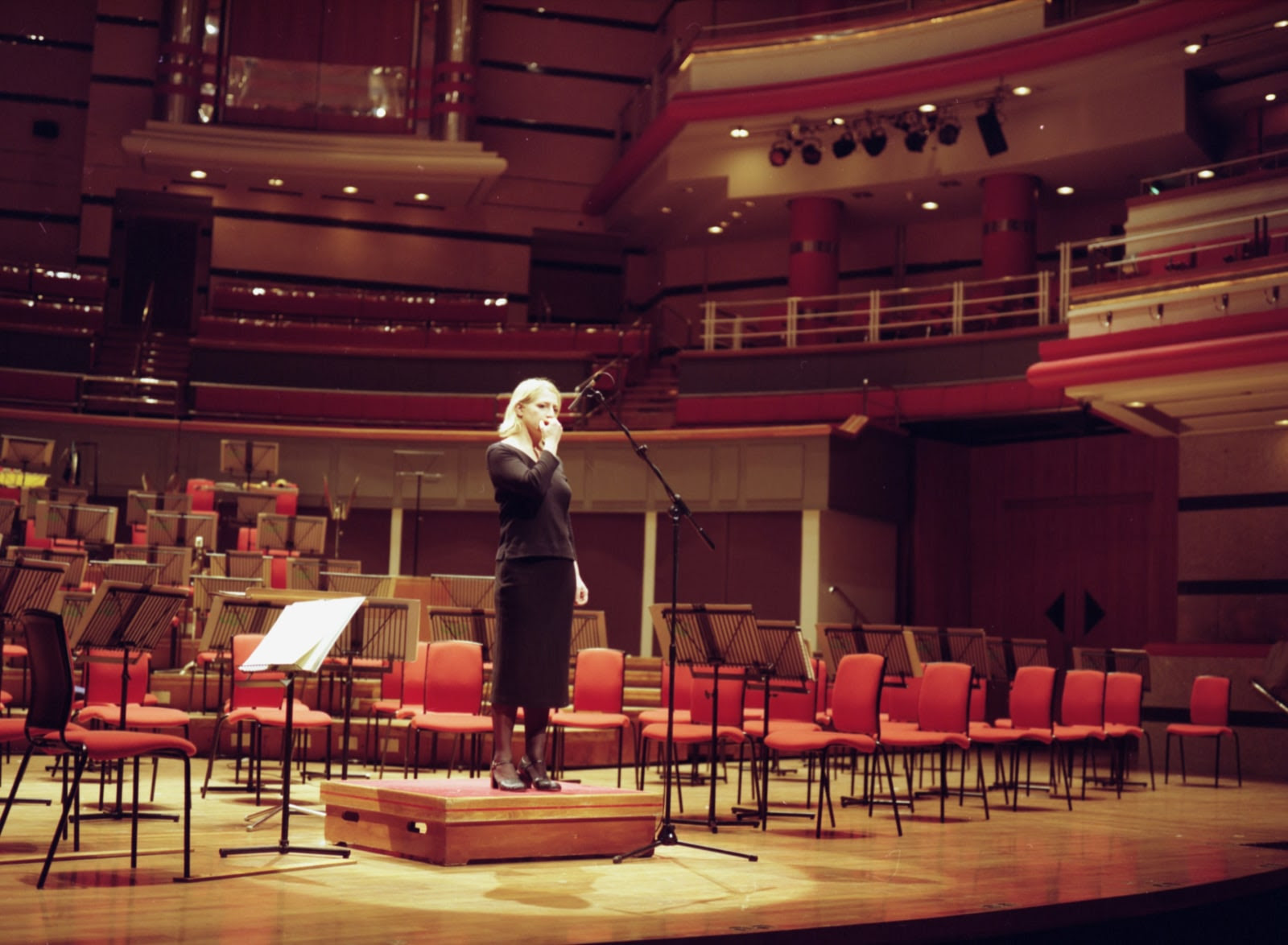 Ceal Floyer on a concert stage biting her nails into a microphone