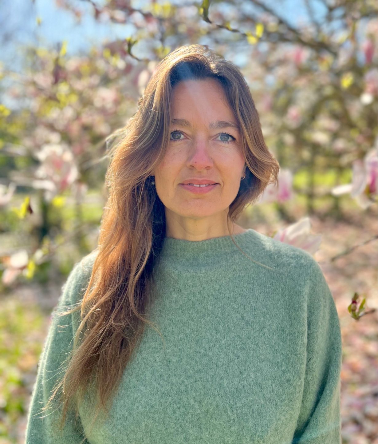 Portrait of Filipa Ramos posing in a graden and wearing a green jumper