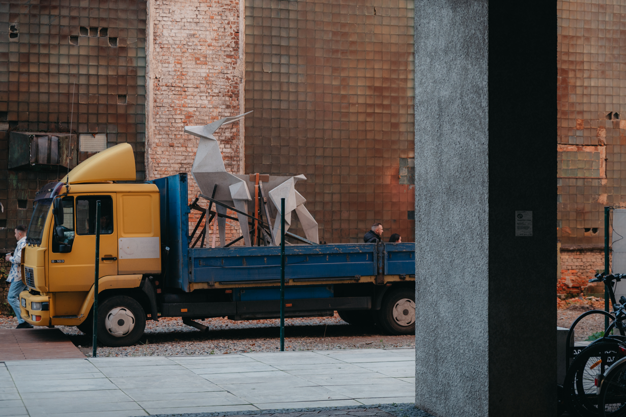 Sculpture of an origami deer strapped to the back of a flatbed truck