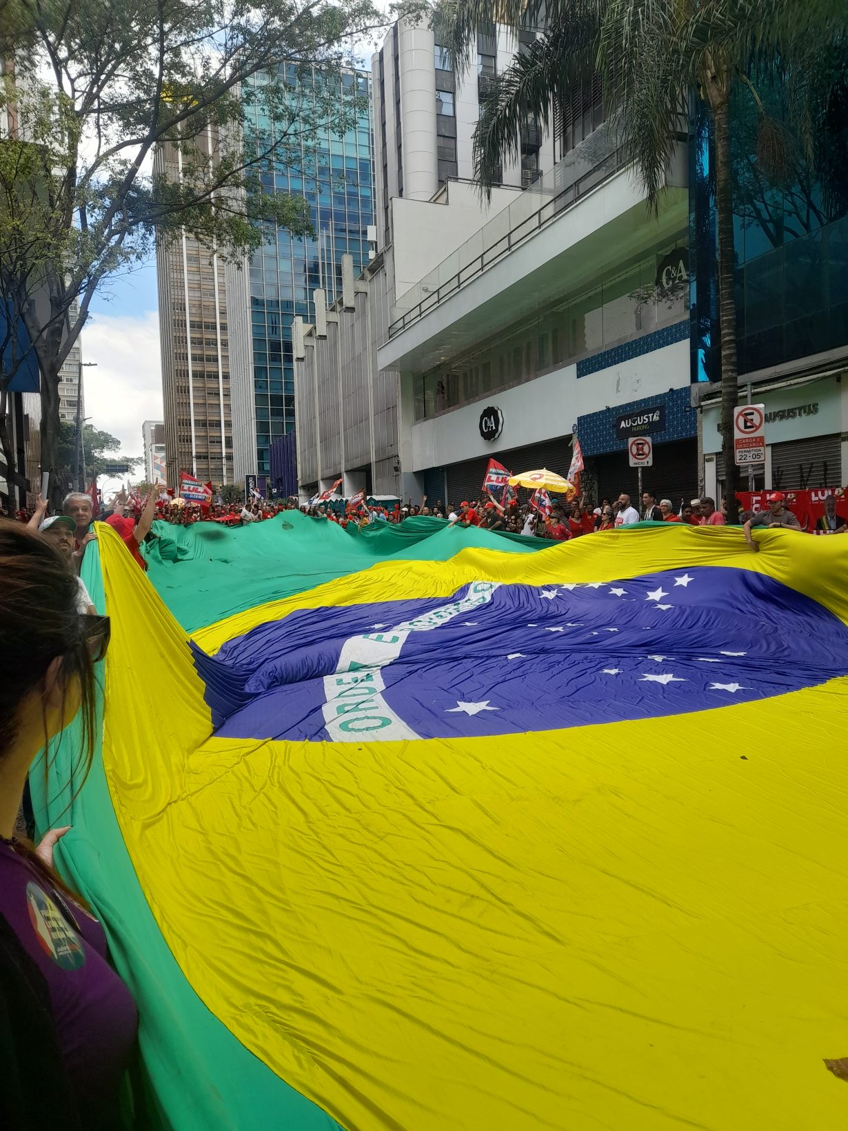 Supporters of President Lula unfurl the Brazilian flag at a street rally ahead of the election. 