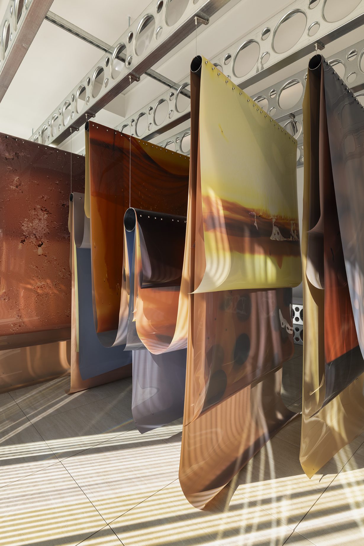 Installation image of Lotus L Kang’s work in situ at the Giardini della Biennale, Venice. In the photo, close up images are hanging from the ceiling fixtures.