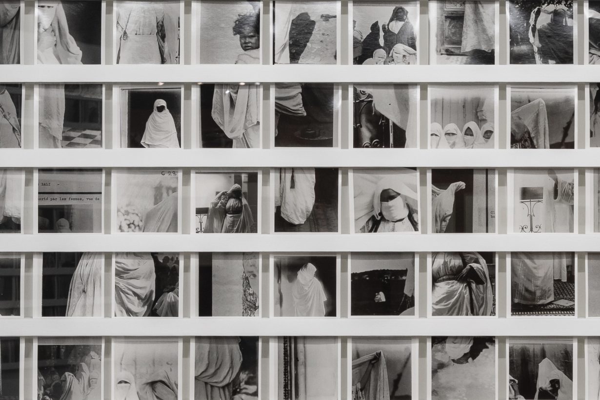 Close-up installation photograph of a compilation of black and white images of women wearing niqabs and children.